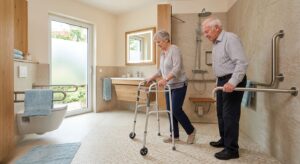 Elderly couple in a bright modern bathroom with curbless shower, grab bars, and slip-resistant tiles, woman using a walker stepping onto shower floor, conveying safety and independence for aging-in-place design.